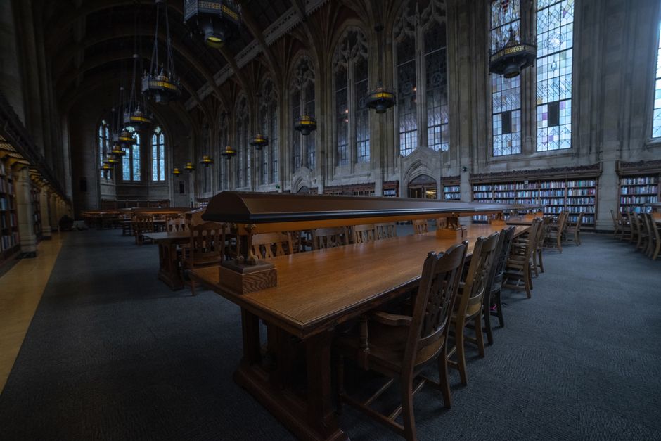A spacious historic library with wooden tables and stained glass windows.