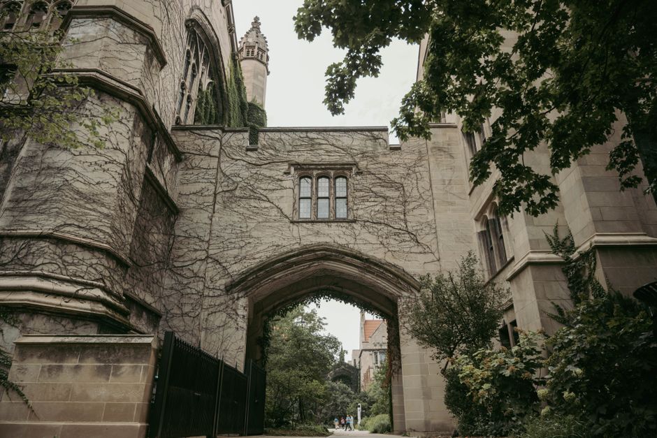 Gothic architecture archway in Chicago, covered with ivy and surrounded by lush greenery.