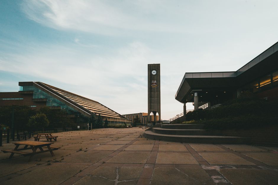 Wide view of clock tower in a modern campus setting with clear skies.